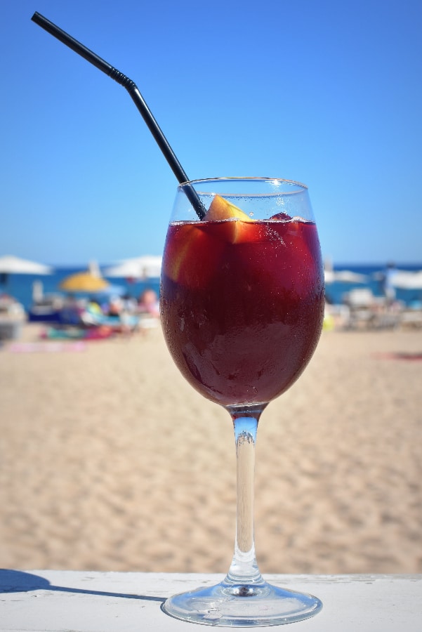 red sangria in a wine glass with straw at the beach