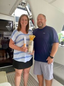 lyle and mary holding the title to their new-to-them 2017 fountaine pajot catamaran and a bottle of champagne to celebrate the purchase